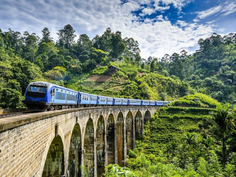Train crossing the Nine Arch Bridge near Ella, surrounded by green hills