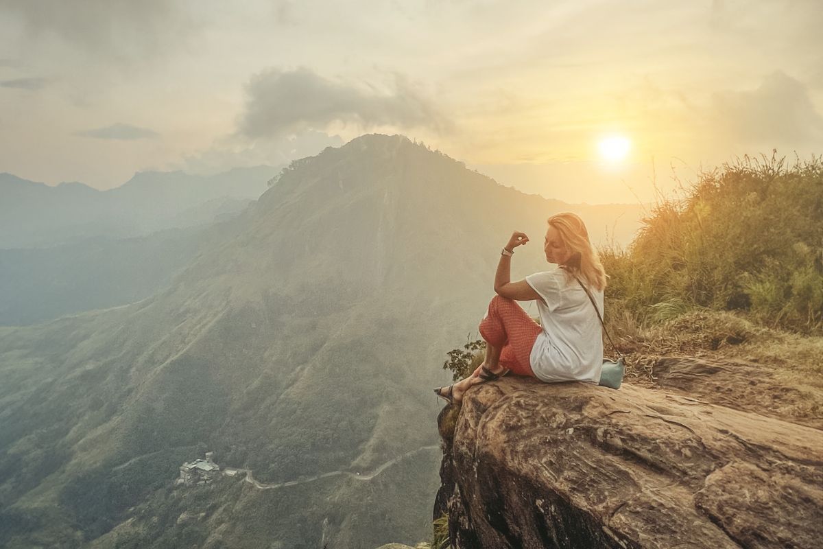 Traveller overlooking Sri Lanka’s misty mountain landscape at sunrise.